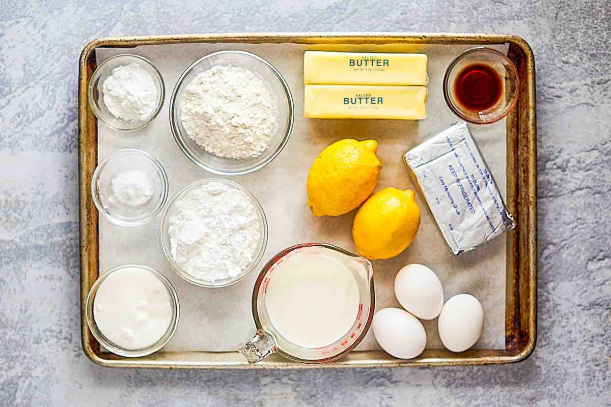 Ingredients for a lemon cake with cream cheese frosting: Milk, eggs, lemons, flour, confectioners sugar, baking powder and soda, vanilla, butter, cream cheese and sugar. Hostess At Heart