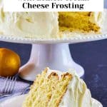 Image for Pinterest of a Slice of easy lemon cake with lemon cream cheese frosting on white plate showing moist yellow layers. The full cake is in the back on a cake stand. Hostess At Heart