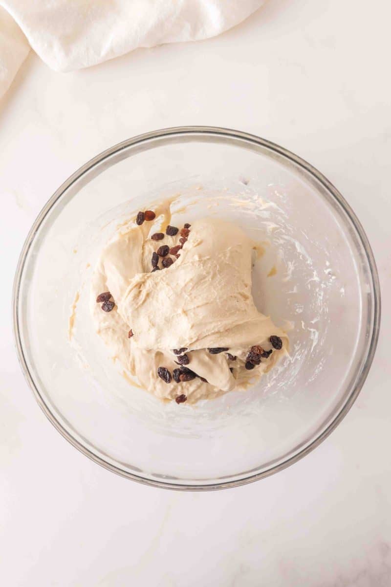 Sticky sourdough bread dough in a mixing bowl with dark raisins after the first fold - Hostess At Heart