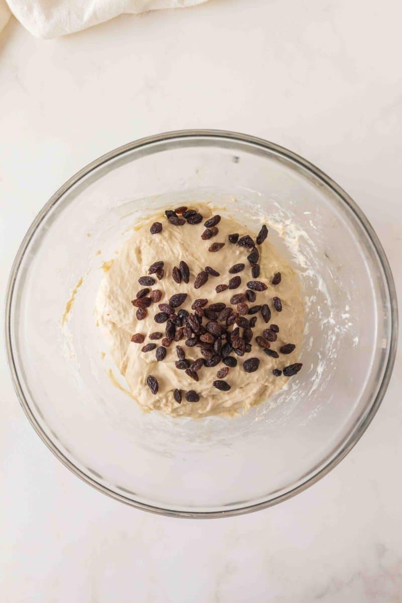 Sticky sourdough bread dough in a mixing bowl with dark raisins on top ready for folding. Hostess At Heart
