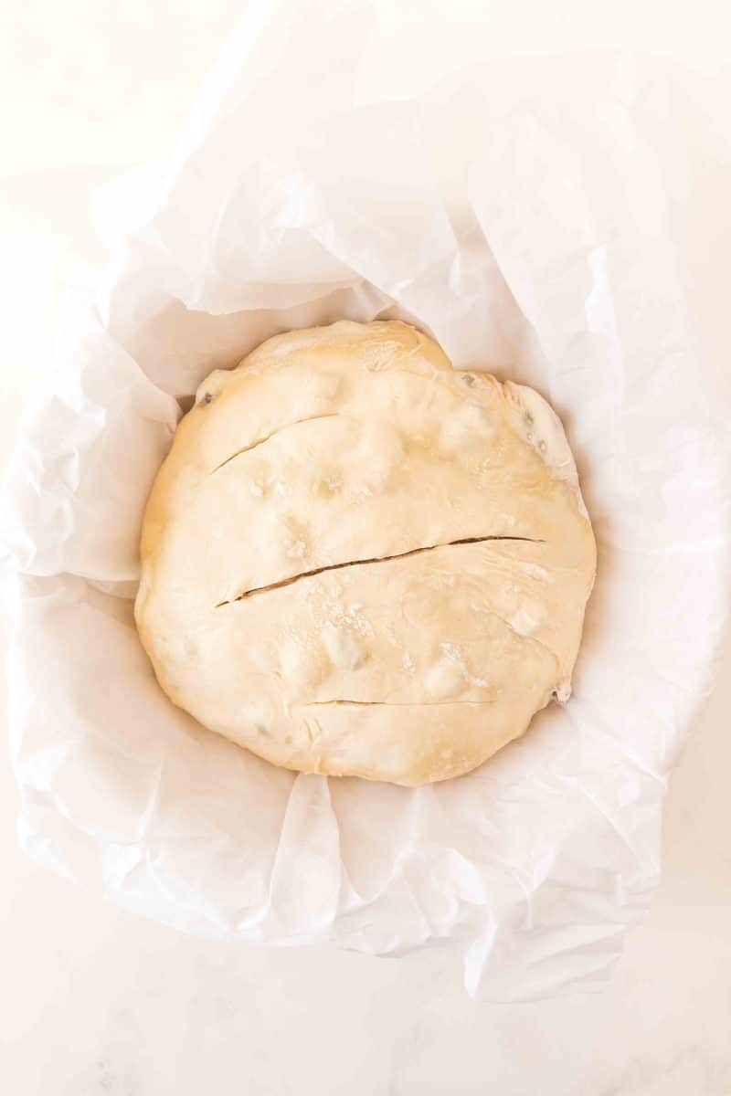 Sourdough cinnamon raisin bread scored three times on top, in a Dutch oven ready to go into the oven. Hostess At Heart