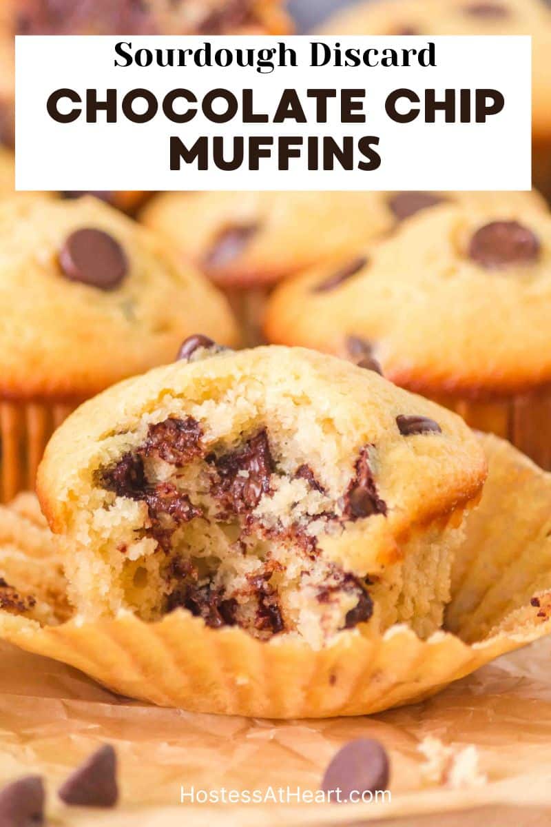 An image for Pinterest of a table view of a sourdough muffin with a bite taken out of it showing melted chocolate chips. Hostess At Heart