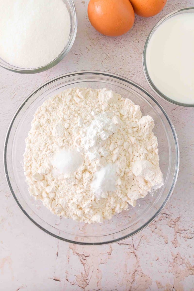 A mixing bowl filled with dry ingredients for homemade sourdough chocolate chip muffins including flour, baking powder and soda, and salt - Hostess At Heart