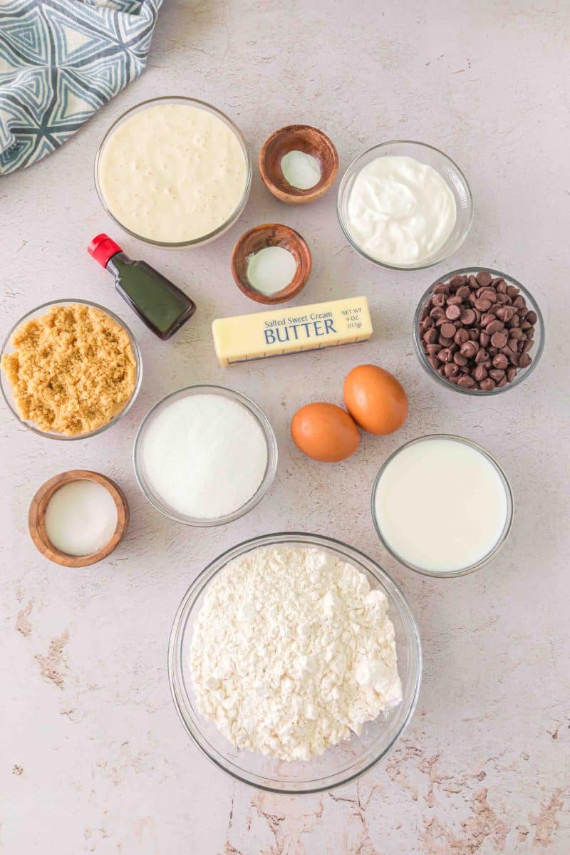 Top down view of chocolate chip sourdough muffin ingredients: Flour, sour cream, sourdough discard, chocolate chips, baking powder and soda, salt, eggs, white and brown sugar, milk, vanilla and butter - Hostess At Heart