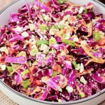 A serving dish filled with an Asian Red Cabbage Salad featuring raw purple cabbage, peppers, carrots, in a ginger dressing garnished with cashews - Hostess At Heart