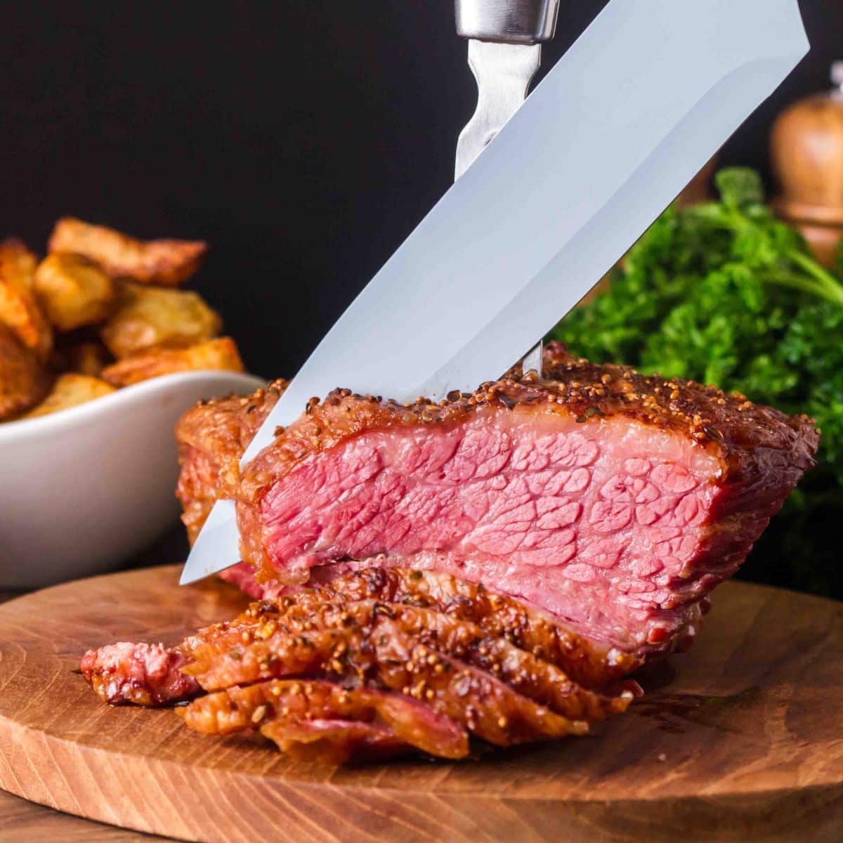 A carving knife cutting into a juicy baked corned beef brisket - Hostess At Heart