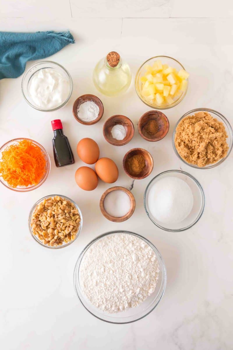 Easy Carrot Bundt Cake Recipe ingredients: flour, sugar, borwn suggar, eggs, shredded carrots, walnuts, baking powder, salt, baking soda, nutmeg, cinnamon, sour cream, pineapple, vanilla, and oil. Hostess At Heart