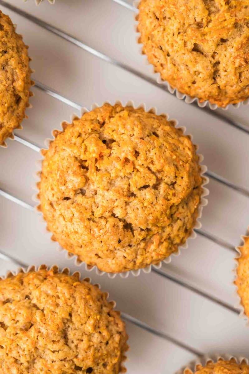 Top down view of carrot cake muffins with golden brown tops sitting on a cooling rack. Hostess At Heart