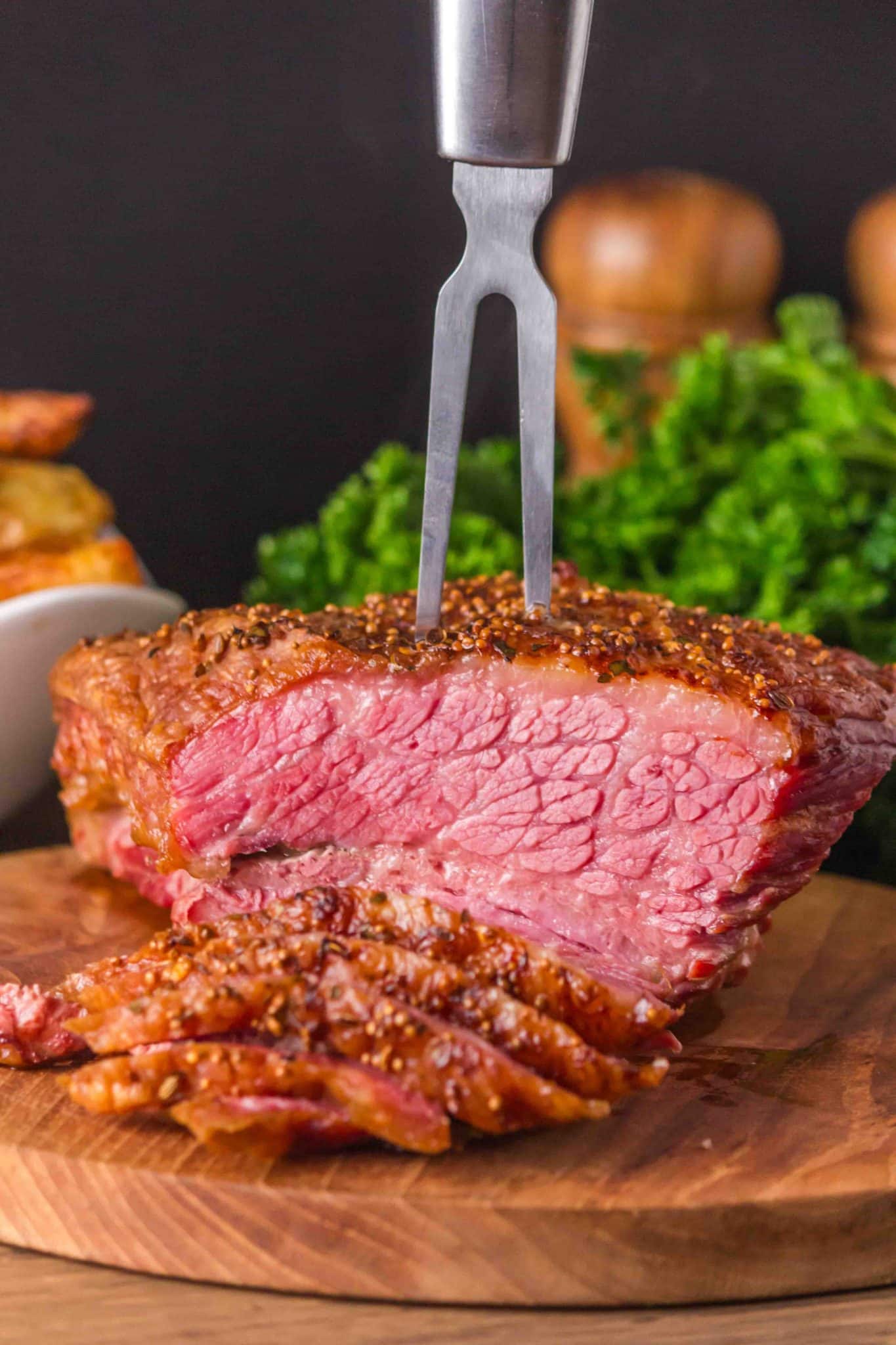 A carving fork holding an oven-baked corned beef brisket in place for carving. Hostess At Heart