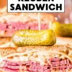 An titled image for Pinterest of a sliced classic corned beef Reuben sandwich that's piled high with Swiss cheese, sauerkraut, and homemade Thousand Island dressing. Hostess At Heart