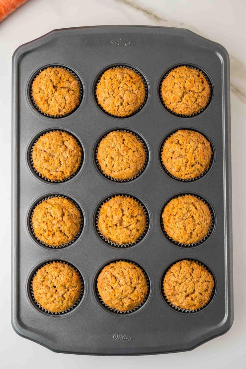 Top down view of a muffin pan filled with freshly baked carrot muffins with cinnamon. Hostess At Heart