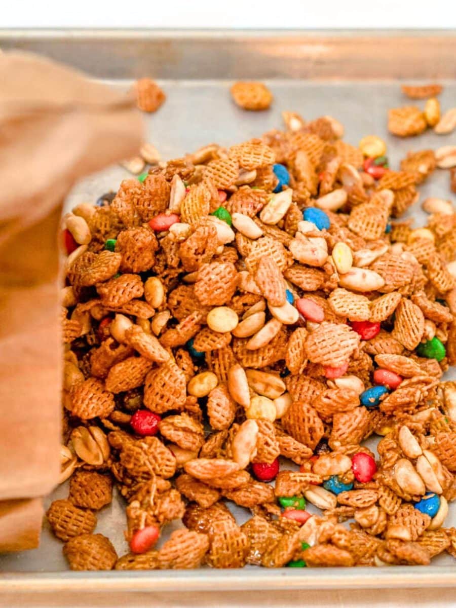 Candy coated crispix cereal snack mix poured out on a baking sheet to dry. Hostess At Heart