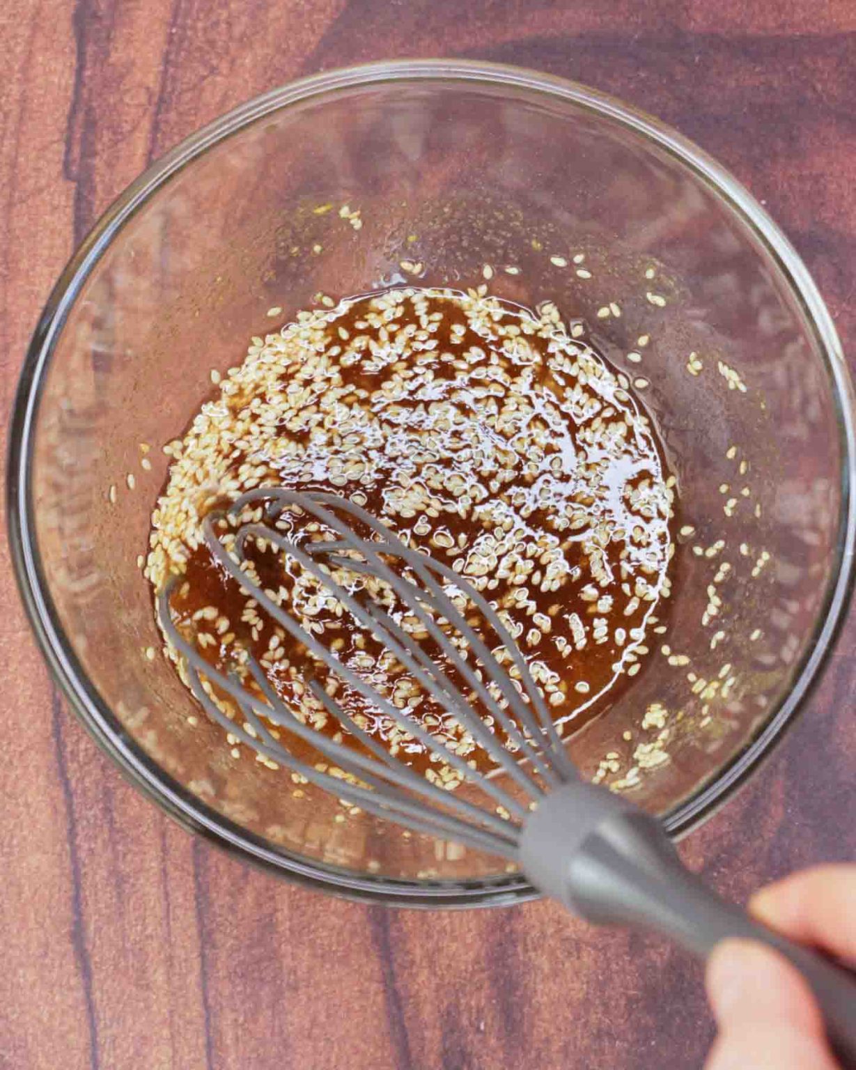 A mixing bowl filled with Ginger sesame dressing being whisked together to make a cabbage salad recipe. Hostess At Heart