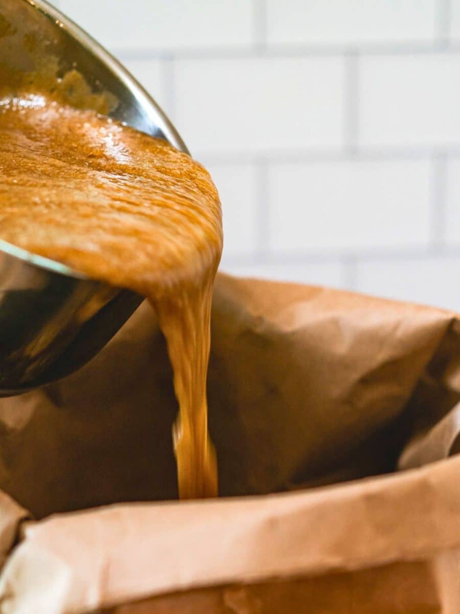 Frothy hot caramel poured into a bag filled with salted peanuts, M&M's, and Crispix cereal to make a homemade sweet snack mix. Hostess At Heart