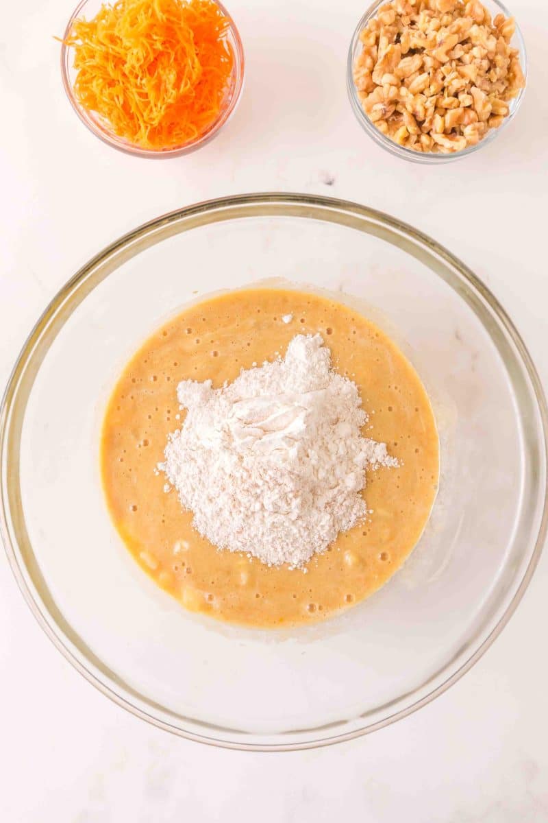 Dry Bundt cake ingredients added to a mixing bowl filled with wet creamed carrot cake ingredients. Hostess At Heart