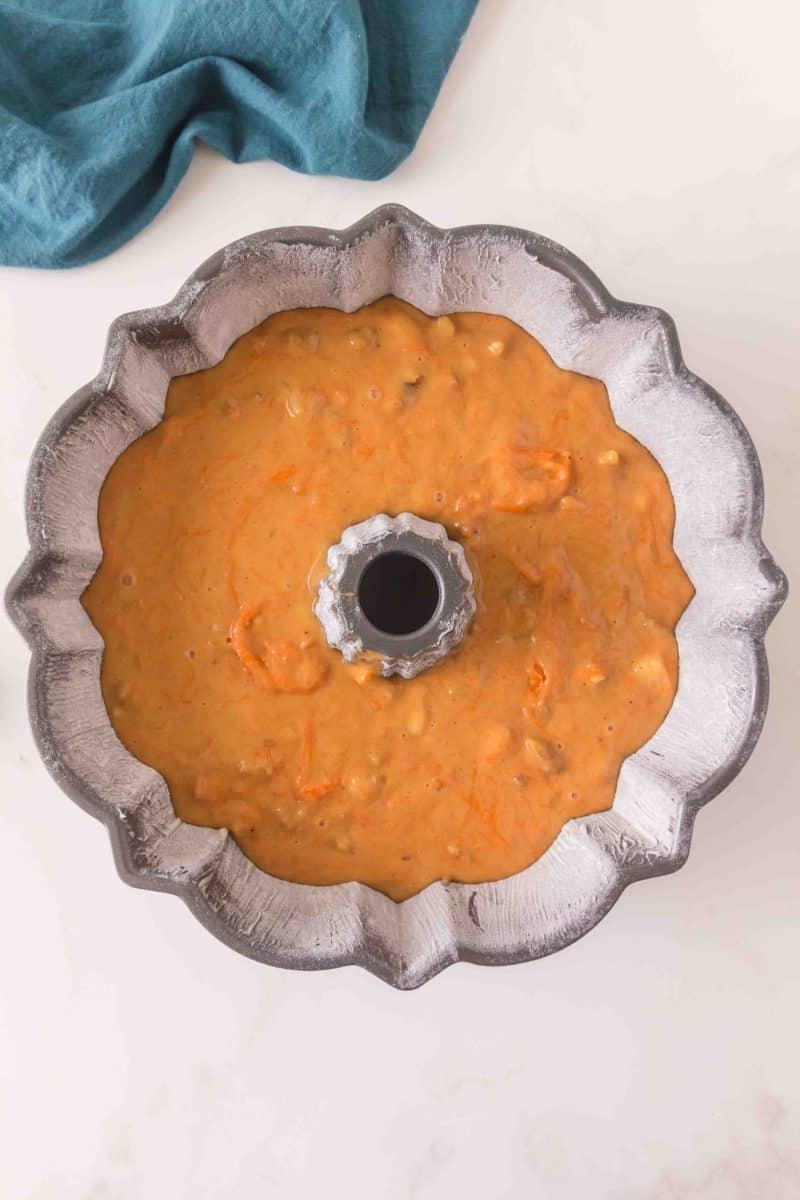 Top down view of a prepared bundt pan filled with a thick carrot bundt cake batter. Hostess At Heart