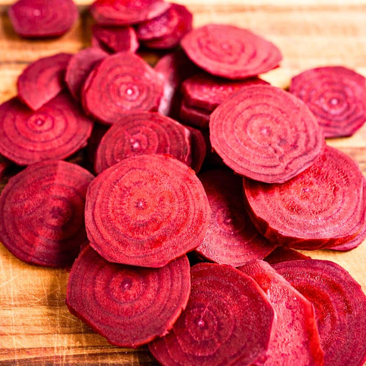 A cutting board filled with sliced beets demonstrating the thickness needed to make a sliced beets recipe. Hostess At Heart
