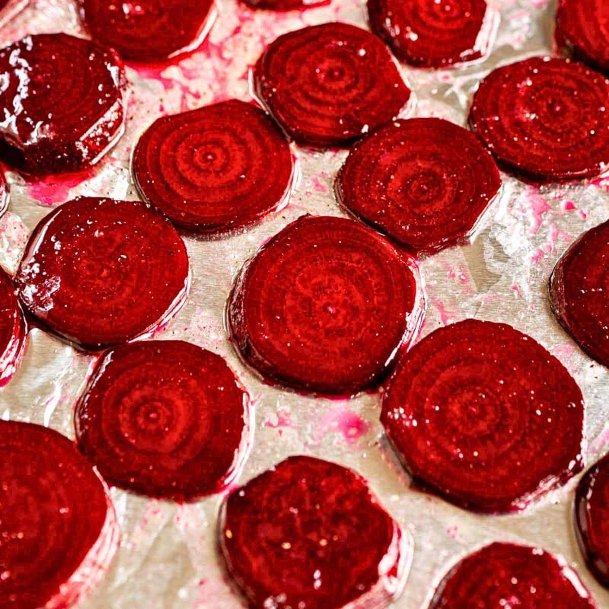A foil-lined baking sheet filled with sliced beets slathered in honey and butter ready for the oven. Hostess At Heart