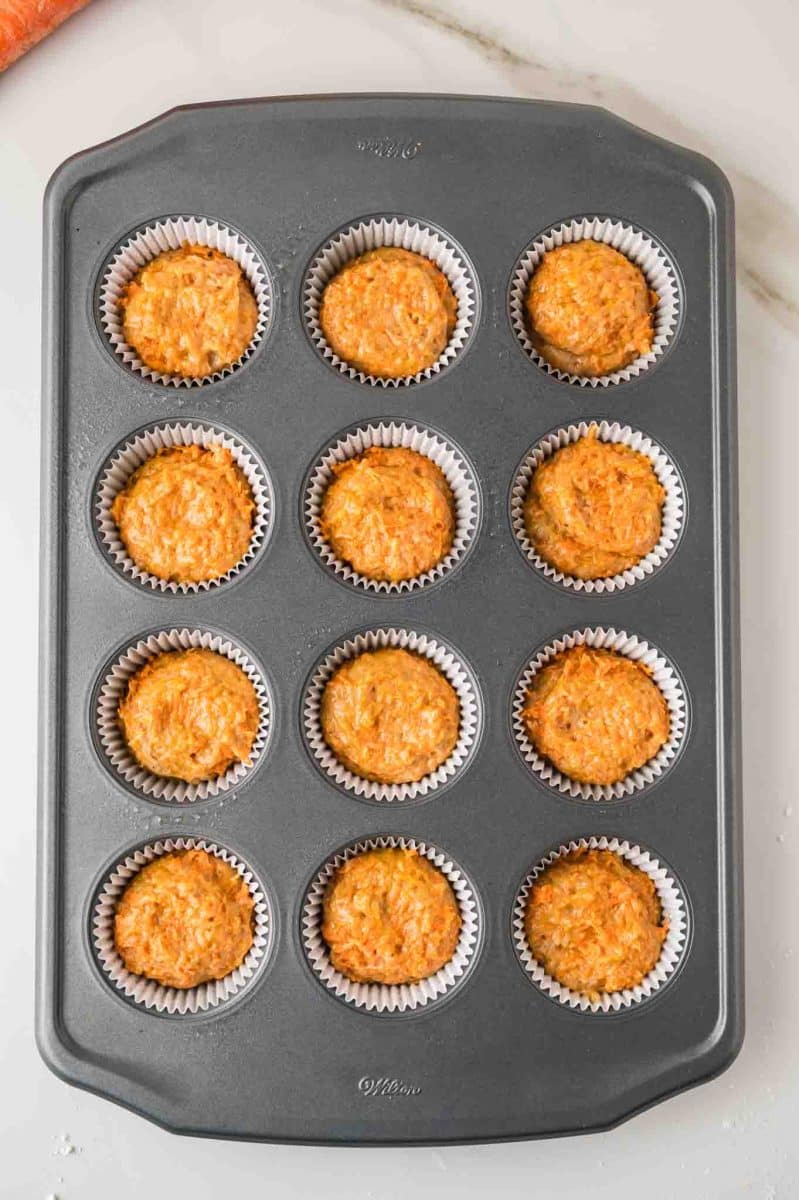 Top down view of a standard muffin pan filled with carrot cake batter to make muffins. Hostess At Heart