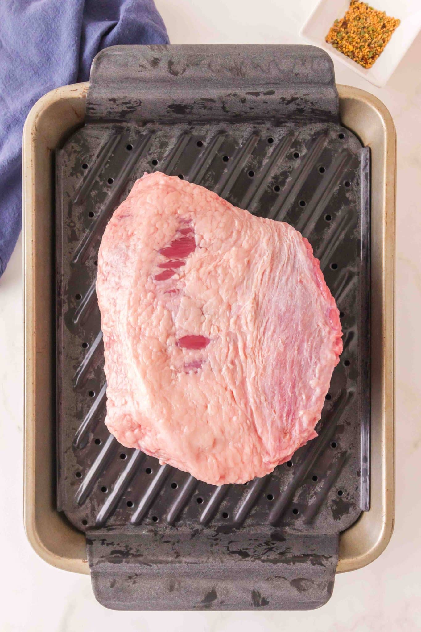 Top down view of a trimmed beef brisket on a baking rack. Hostess At Heart
