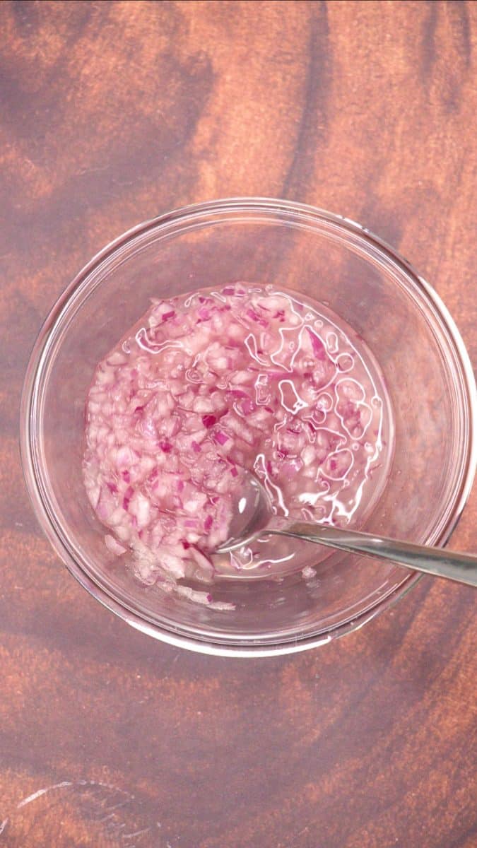 Diced red onion and lime juice in a mixing bowl to mellow the heat of the onion for a fresh avocado salsa salad. Hostess At Heart