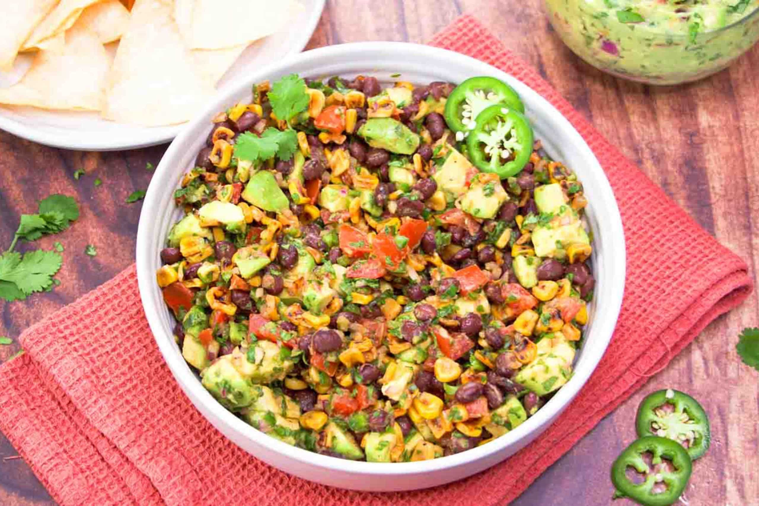 Angled view of a Avocado Salsa Dip served with tortilla chips for a summer appetizer. Hostess At Heart