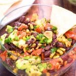 Avocado Corn Salsa served as a chip dip appetizer with tortilla chips on the side. Hostess At Heart