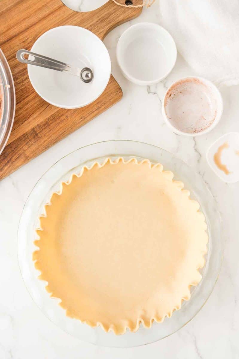 Top down view of a fluted unbaked pie crust in a pie plate. Hostess At Heart