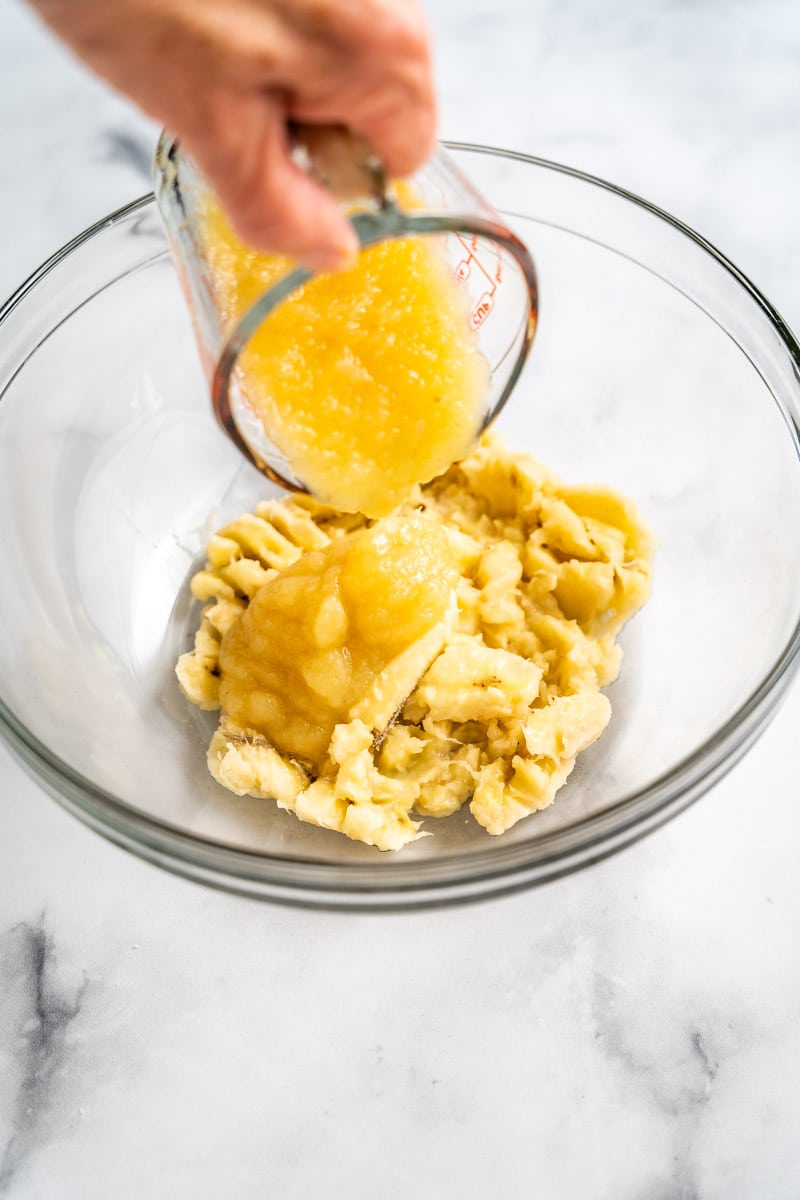 Applesauce added to mashed bananas in a mixing bowl to make Banana Blueberry Muffins Recipe. Hostess At Heart
