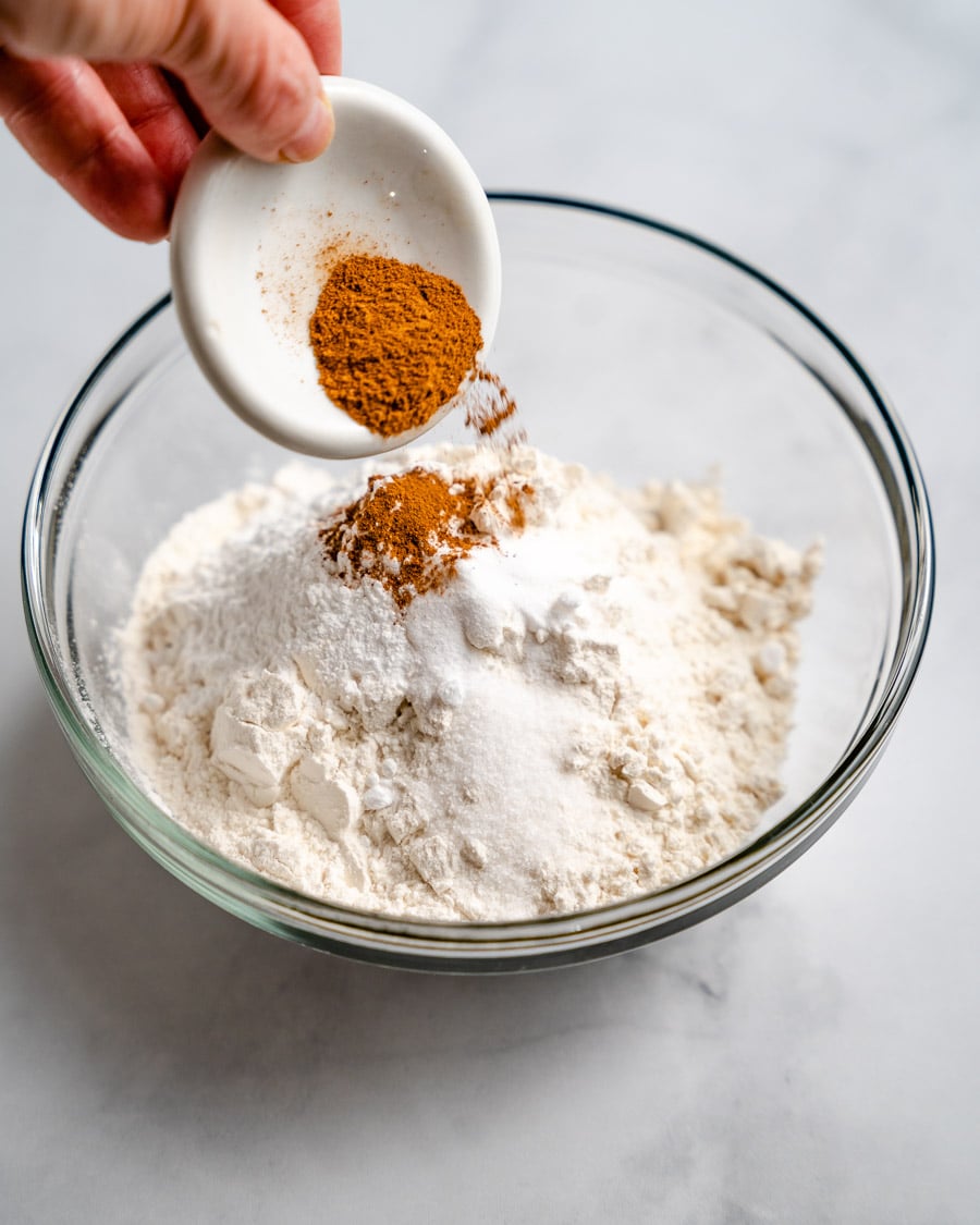 Ground cinnamon added to a bowl of a blueberry banana muffin dry ingredients - Hostess At Heart