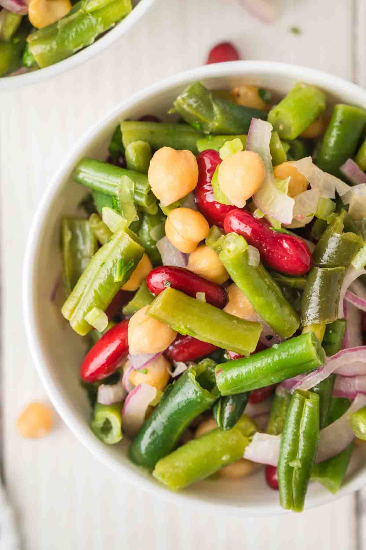 Top down view of a close-up of a quick three bean salad recipe with fresh parsley and colorful beans that will feed a crowd, perfect for cookouts. Hostess At Heart