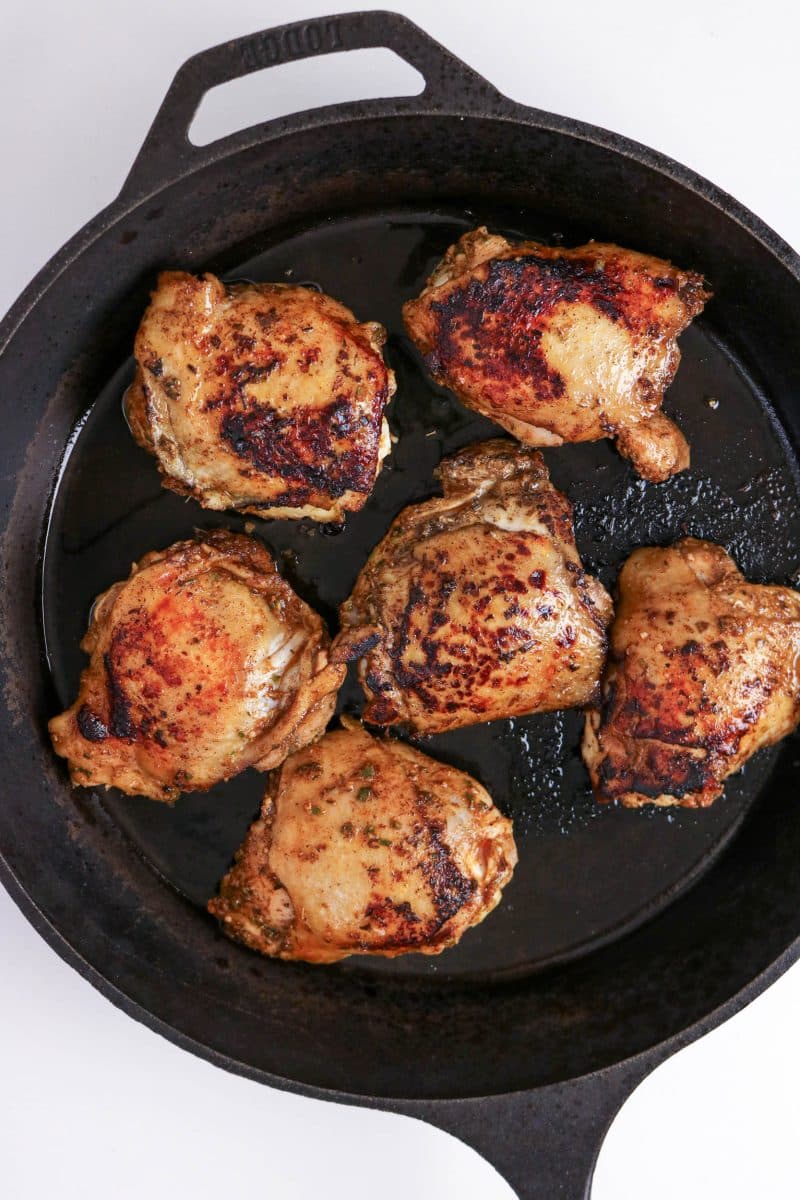 Jerk chicken thighs searing skin-side up in a cast iron skillet. Hostess At Heart