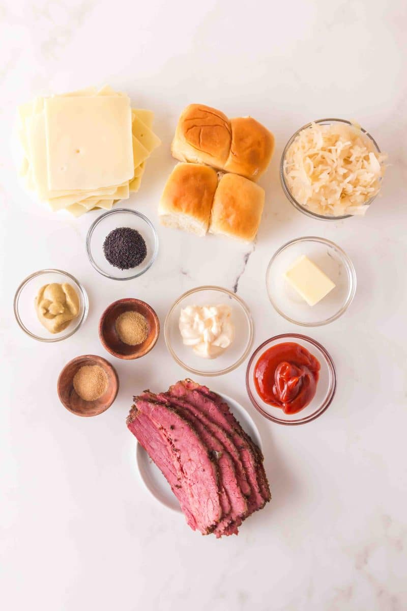 Corned Beef Sliders Recipe Ingredients: Sliced corned beef, sauerkraut, Swiss cheese, Hawaiian bread rolls, ketchup, Dijon mustard, butter, poppyseeds, mayo, garlic powder, and onion powder. Hostess At Heart