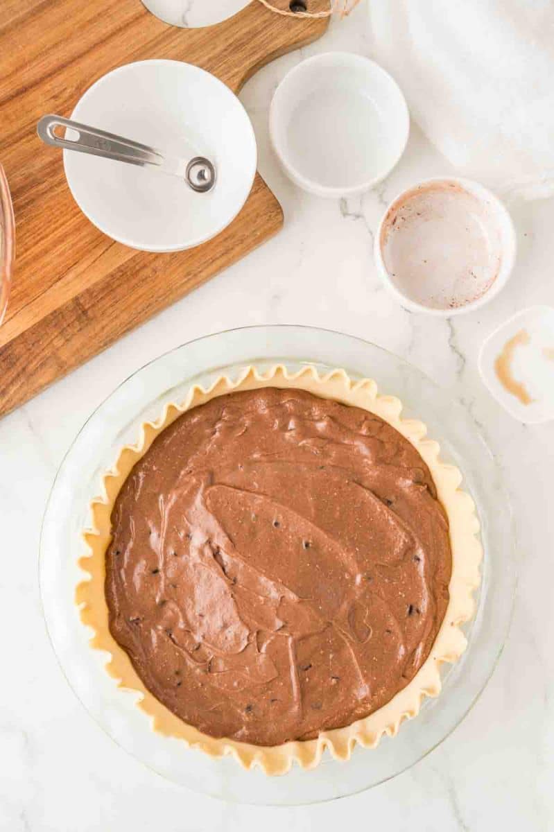 Top down view of an unbaked pie crust filled with chocolate fudge pie batter ready to be baked. Hostess At Heart