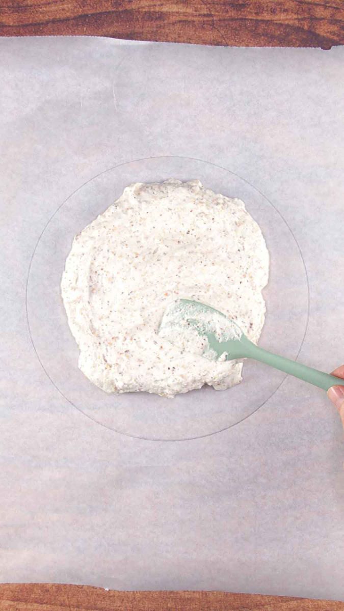 First layer of dacquoise layer spread over a parchment paper circle. Hostess At Heart