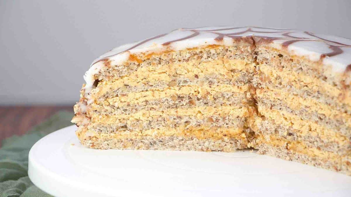 Side view of a slice of Esterhazy cake showing layers of hazelnut meringue and buttercream. Hostess At Heart