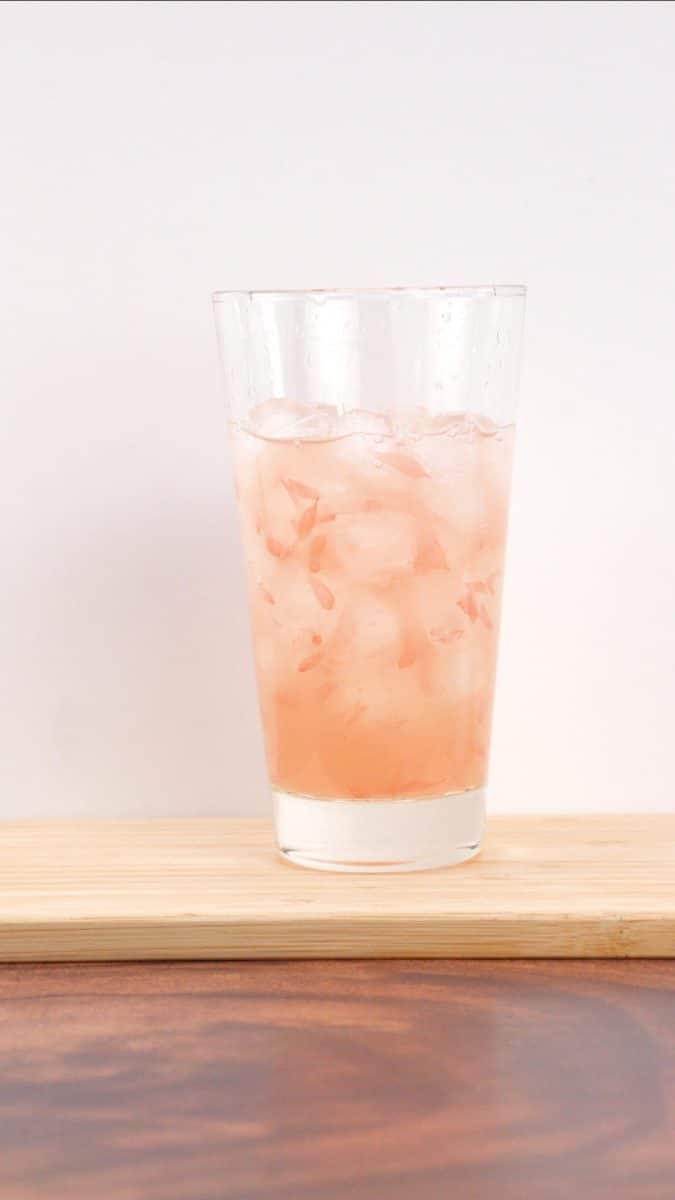 Sideview of a Tom Collings glass filled with a mixed paloma drink over ice. Hostess At Heart