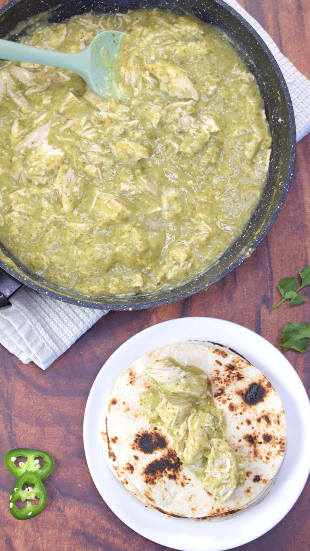 Top down view of a toasted tortilla being filled with chicken green mole sauce. Hostess At Heart