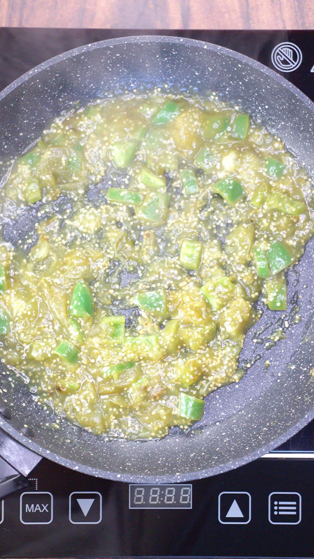 Tomatillos and chopped jalapenos being sauteed together in a large skillet to make green mole sauce for chicken enchilada recipe. Hostess At Heart