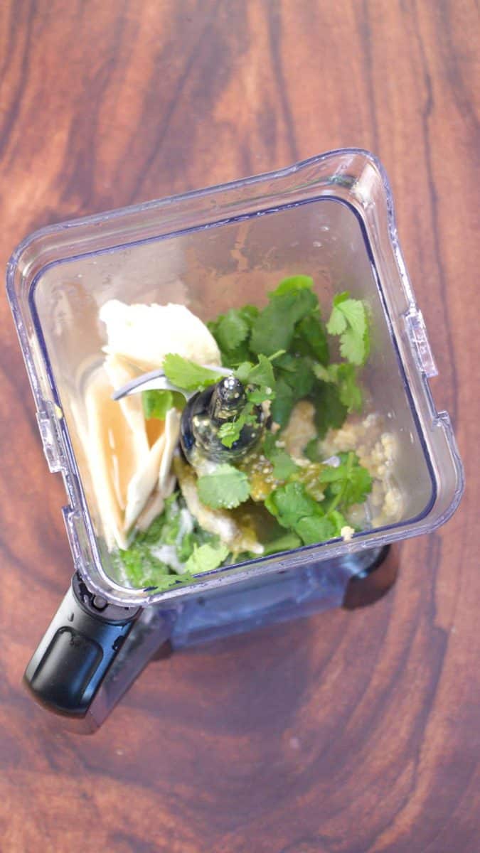 Green mole sauce being blended in a blender with cilantro, garlic, and flour tortilla pieces. Hostess At Heart