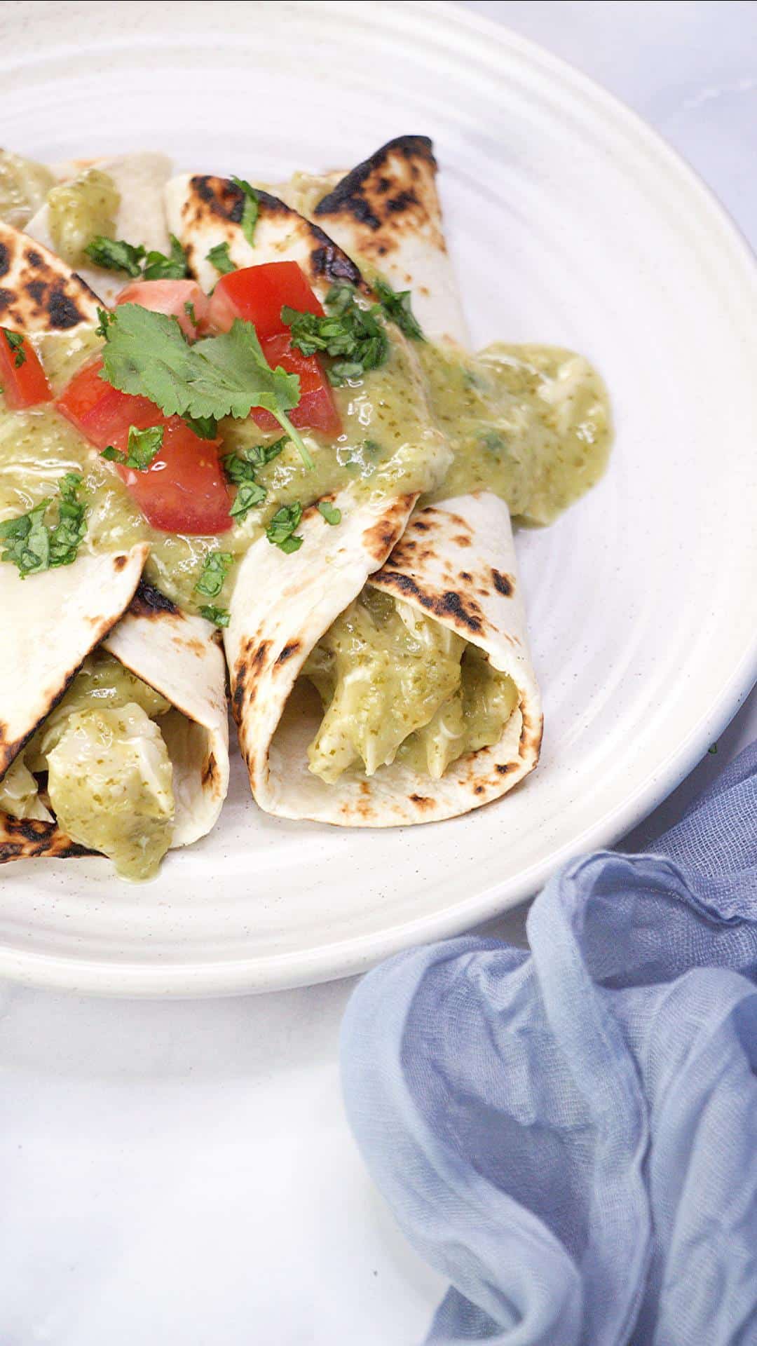 Two green mole chicken enchiladas on a plate smothered in homemade jalapeno tomatillo mole sauce and garnished with fresh cilantro. Hostess At Heart
