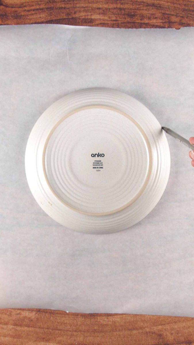 A piece of parchment paper topped with a dinner plate to create a template for a Austrian Layer Cake. Hostess At Heart