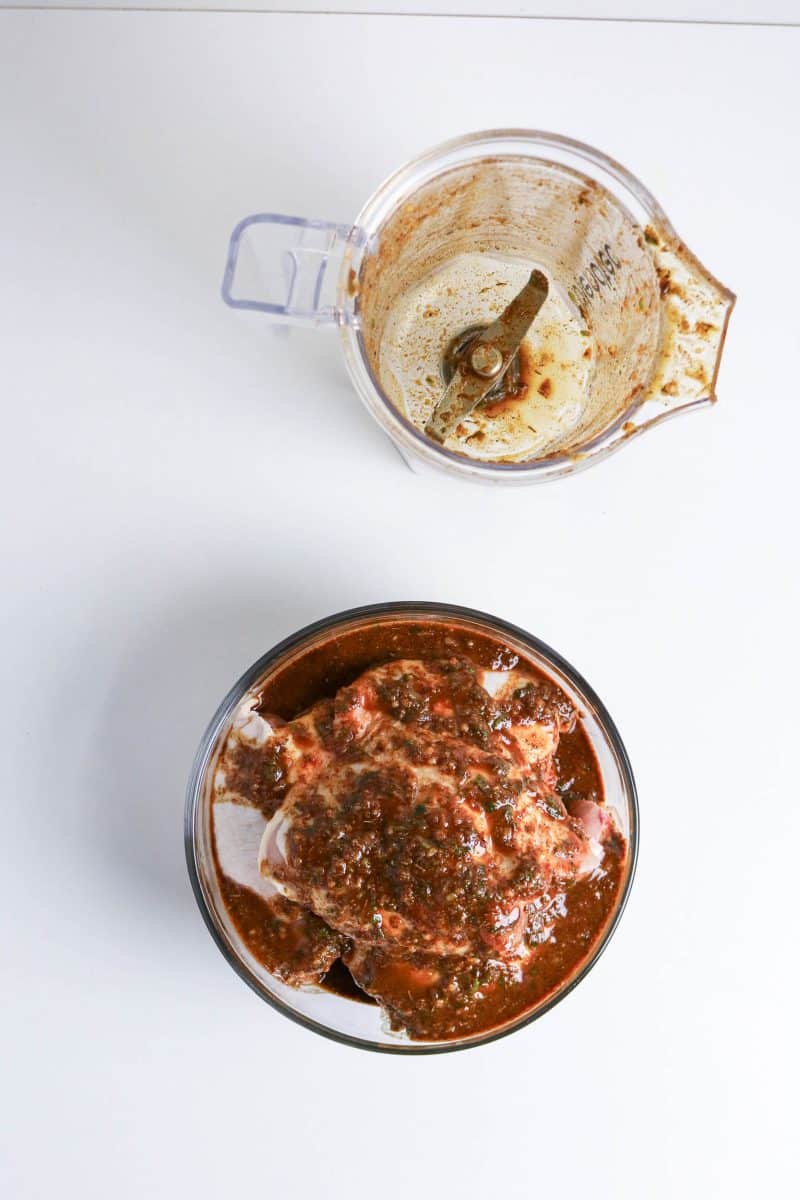 Raw Chicken thighs coated in jerk marinade in a bowl ready to refrigerate. Hostess At Heart