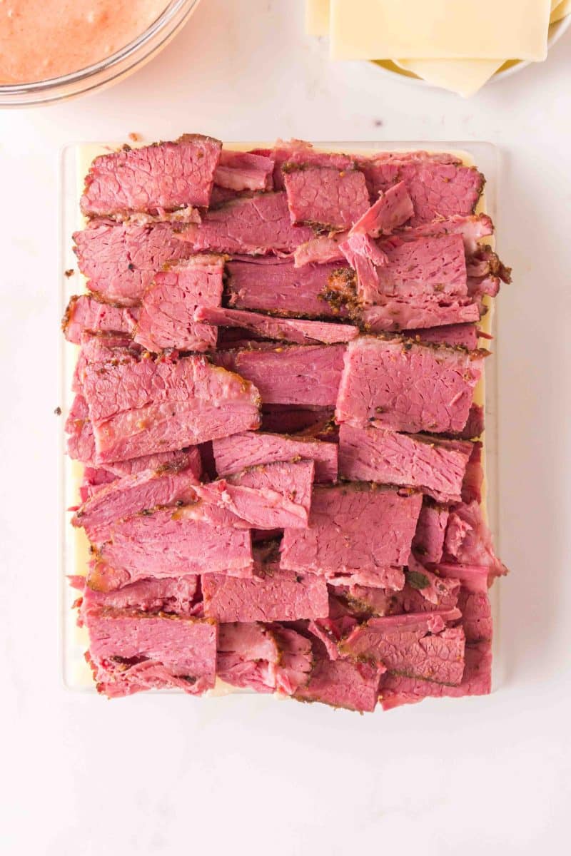 Layering corned beef on Hawaiian rolls to make game day sliders. Hostess At Heart