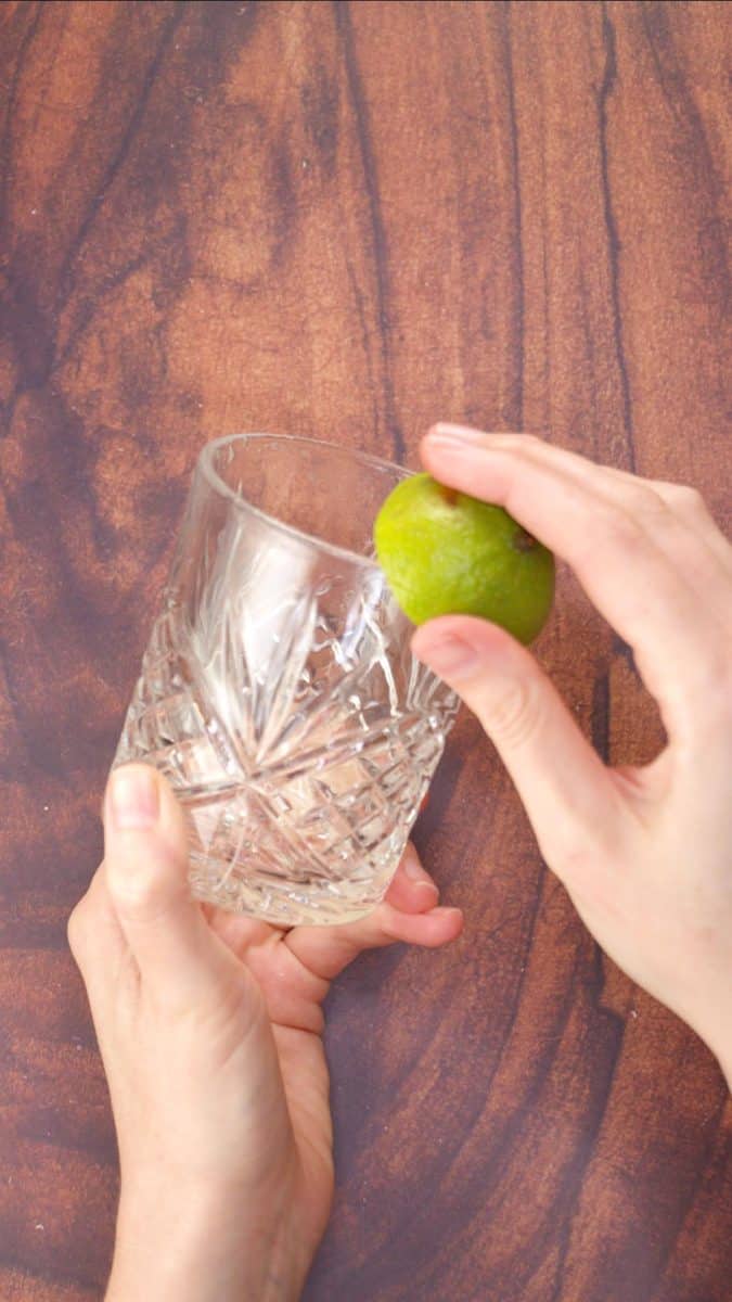 Rimming a lowball glass with a wedge of lime so that it can be rimmed next with salt. Hostess At Heart