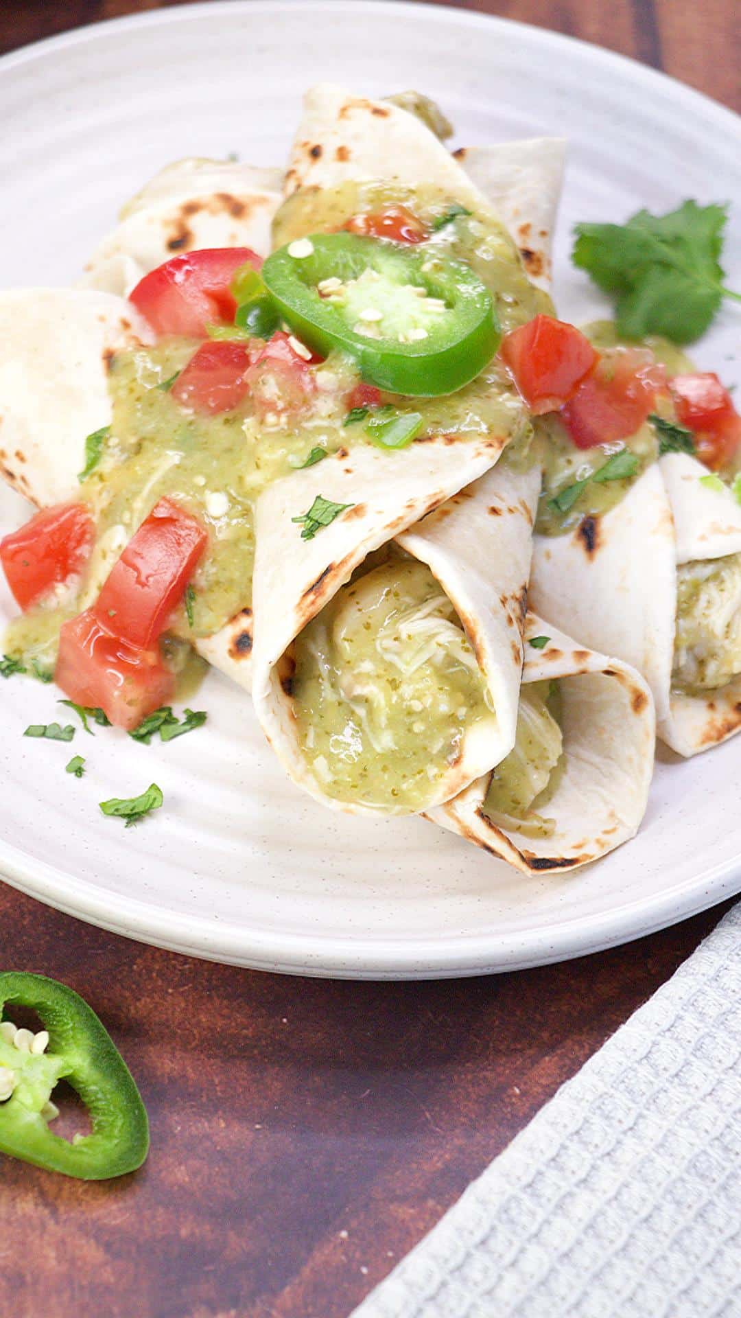 Two green chili chicken enchiladas crossed over each other then smothered in jalepeno tomatillo cause and garnished with fresh cilantro. Hostess At Heart