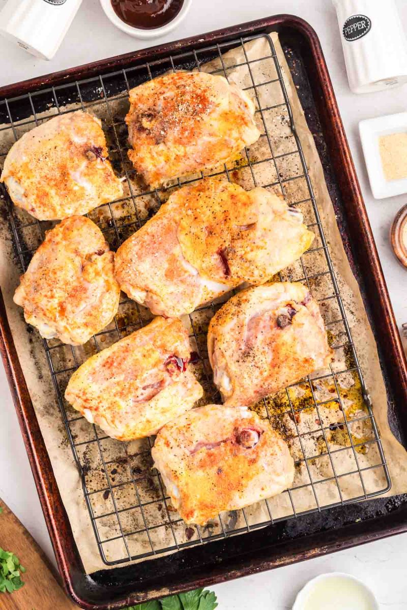 Bone-in Chicken thighs skin side down on a wire rack baking sheet before barbecue sauce is applied. Hostess At Heart