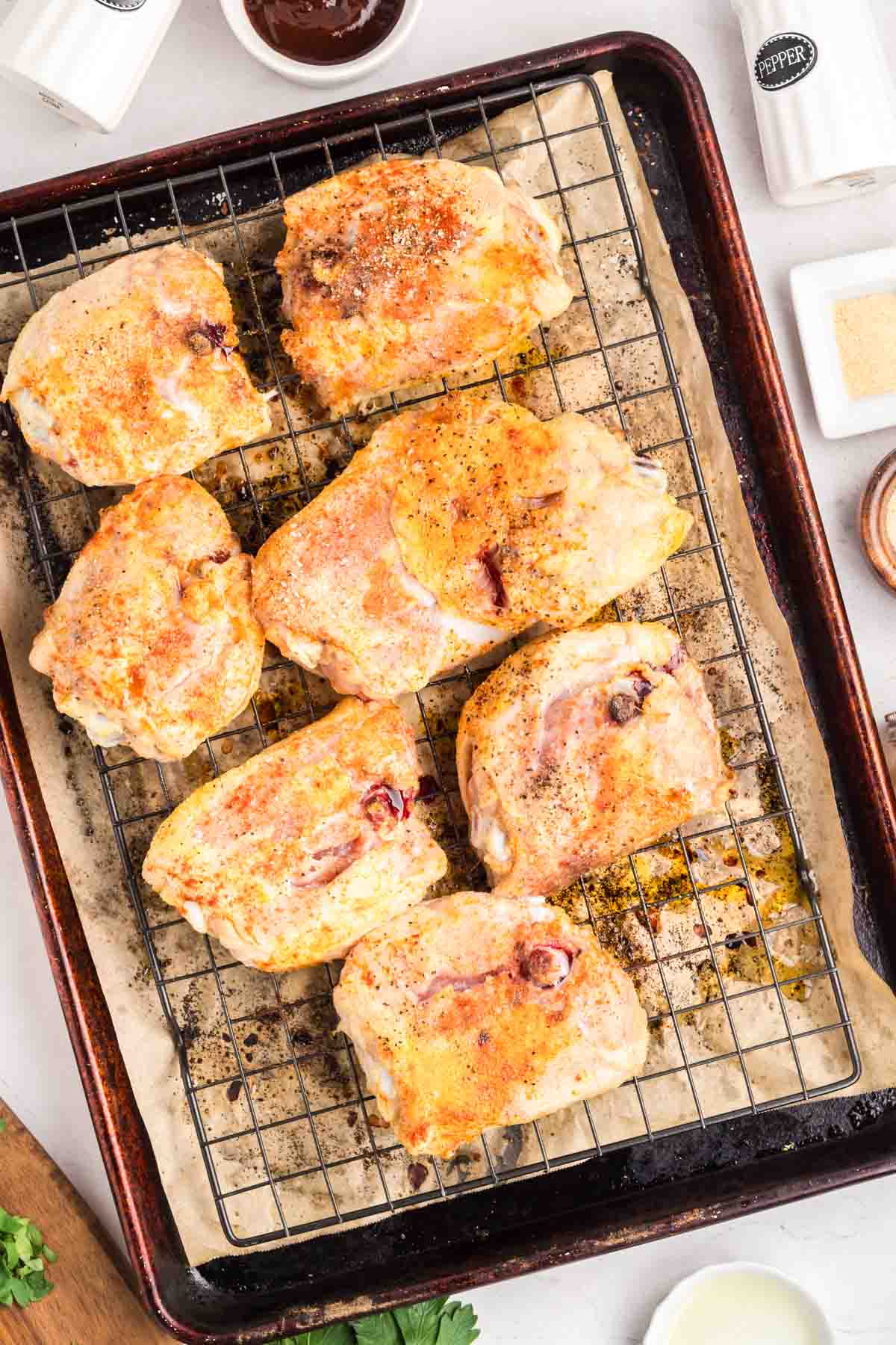 Bone-in Chicken thighs skin side down on a wire rack baking sheet before barbecue sauce is applied. Hostess At Heart