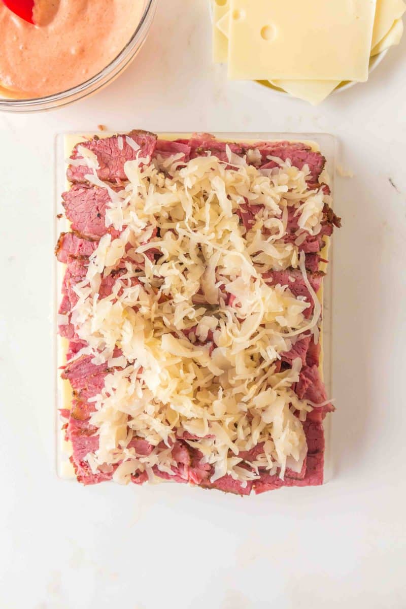 Layering corned beef, swiss cheese, and sauerkraut on Hawaiian rolls to make corned beef party sliders. Hostess At Heart