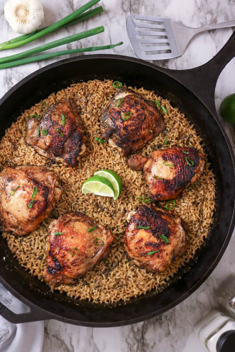 Jerk Chicken and Rice in a cast iron skillet garnished with lime and green onions. Hostess At Heart